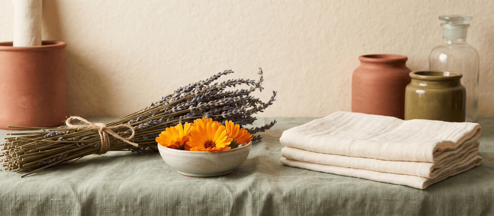 Calendula flowers and dried lavender beside folded gauze on linen