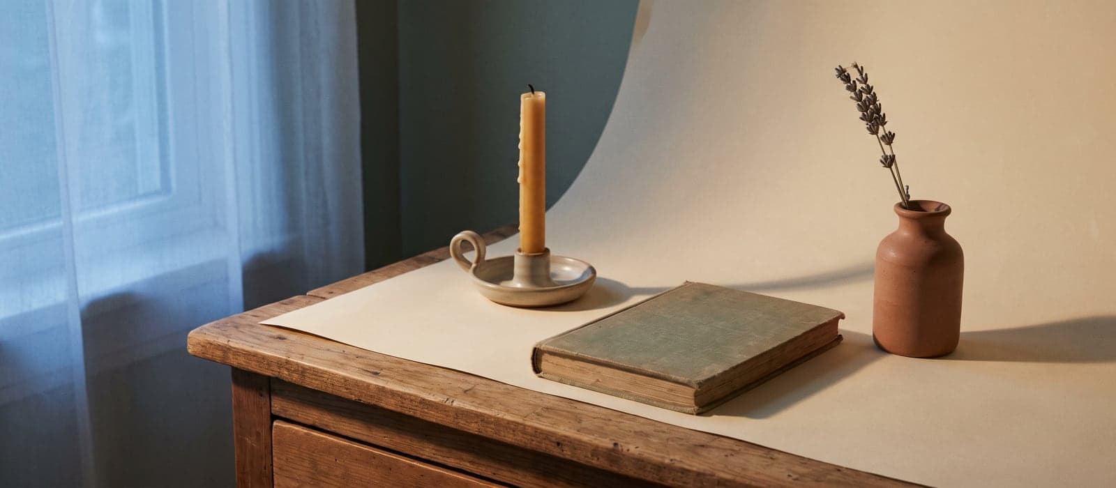 Bedside table at dusk with a candle, closed journal, and lavender