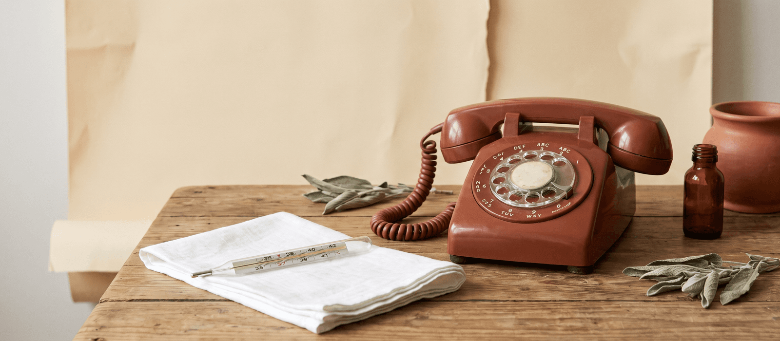 Analog thermometer on folded cloth beside a vintage telephone