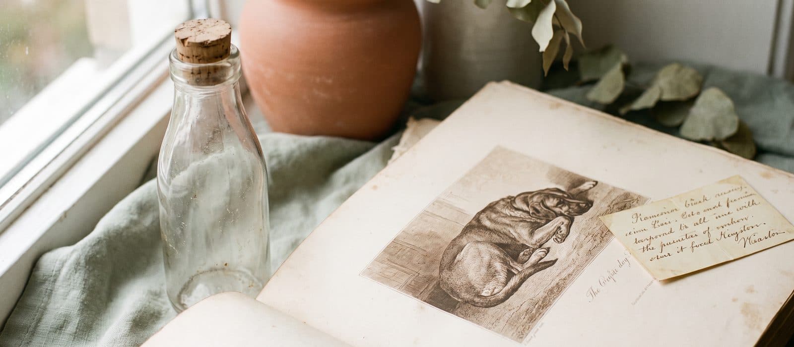 Antique glass milk bottle beside a vintage dog engraving